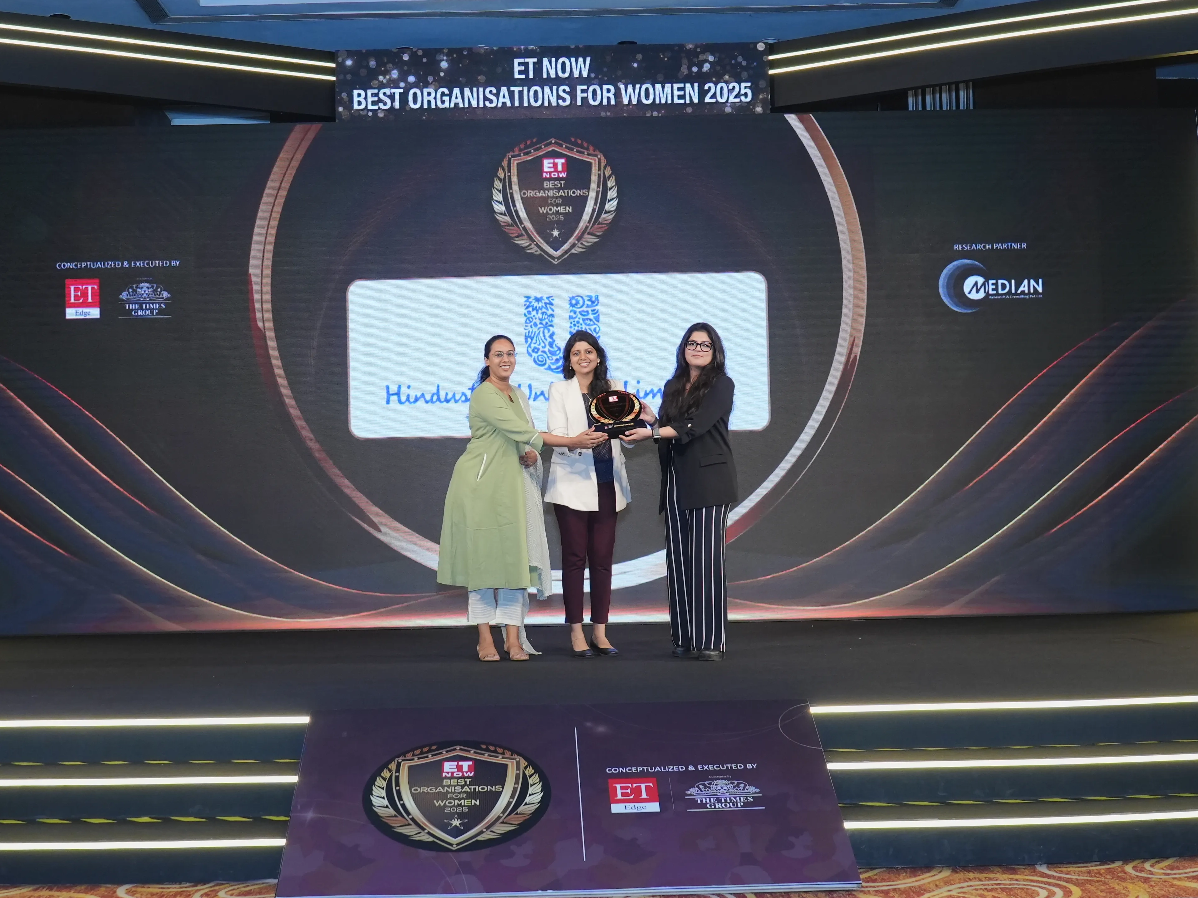 People standing on stage holding the Best Organisation for Women award.