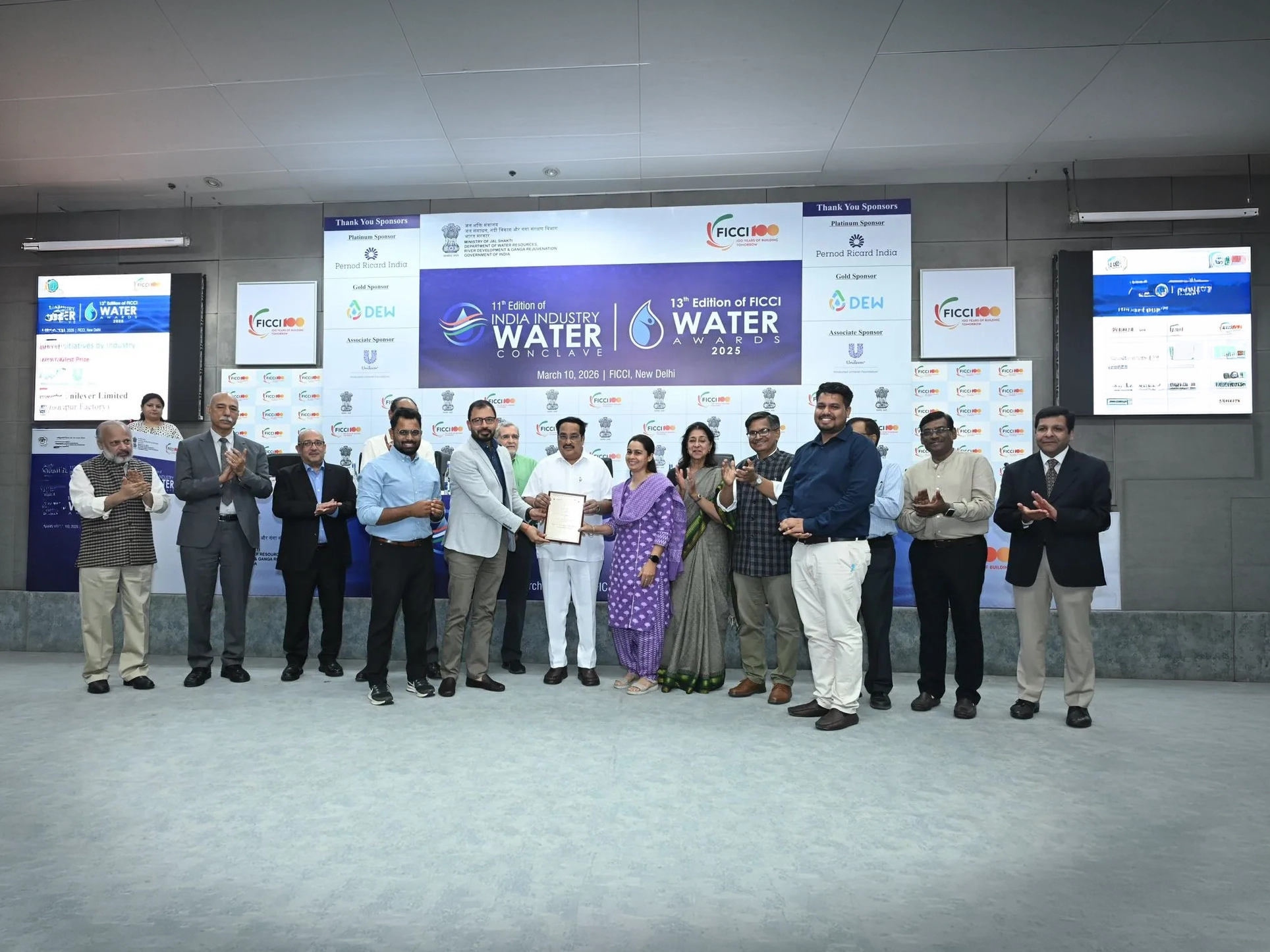 Team holding the FICCI Water Award on stage.