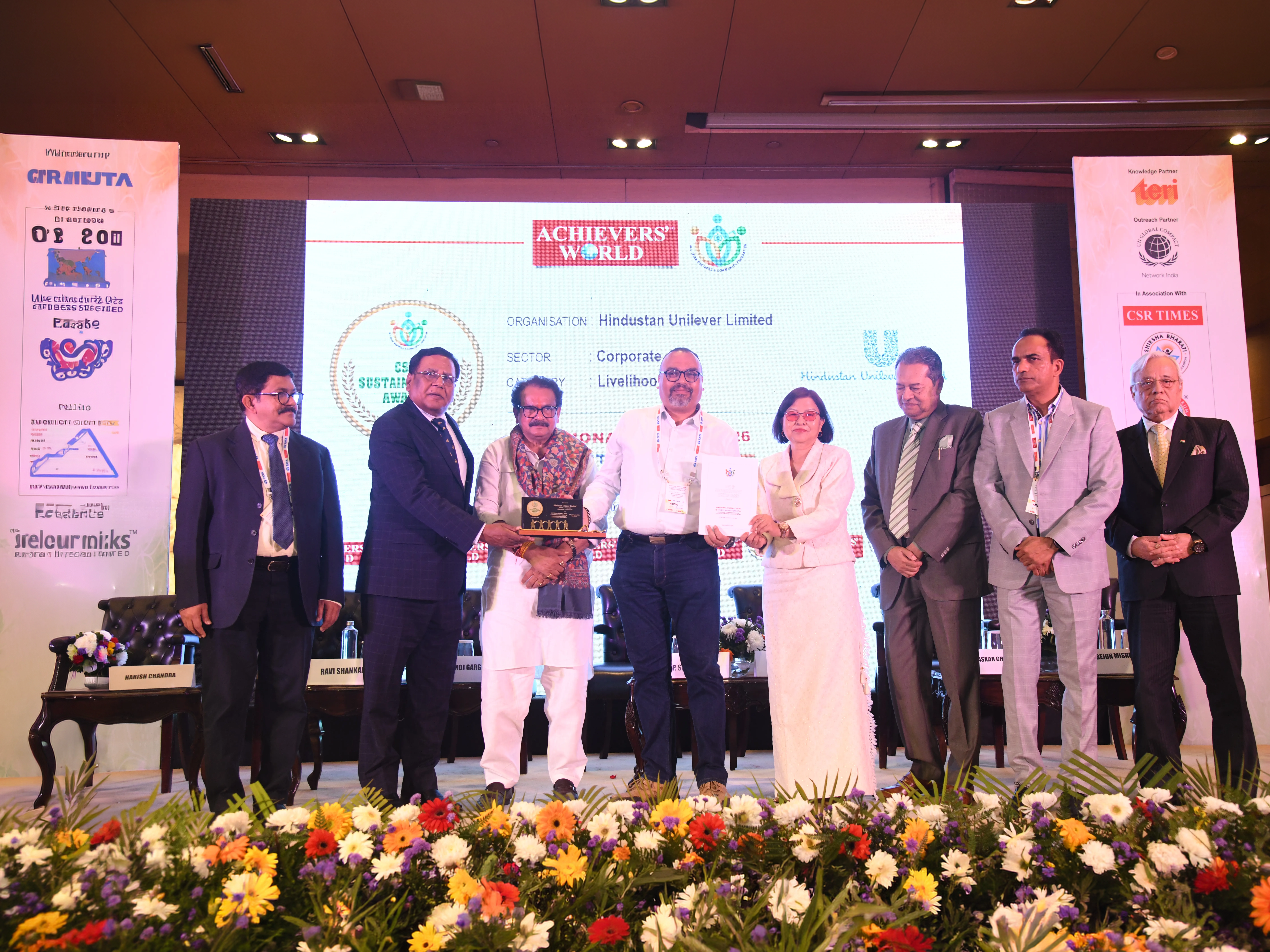 People posing with the C S R Times Award on stage.