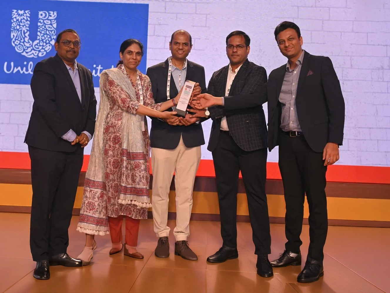 Team receiving the Times of India Social Impact award on stage.