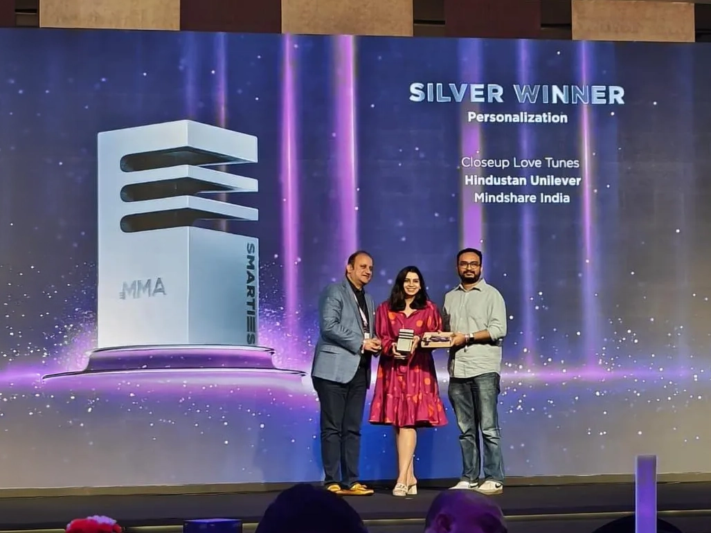 Two people holding the Smarties India award on stage.