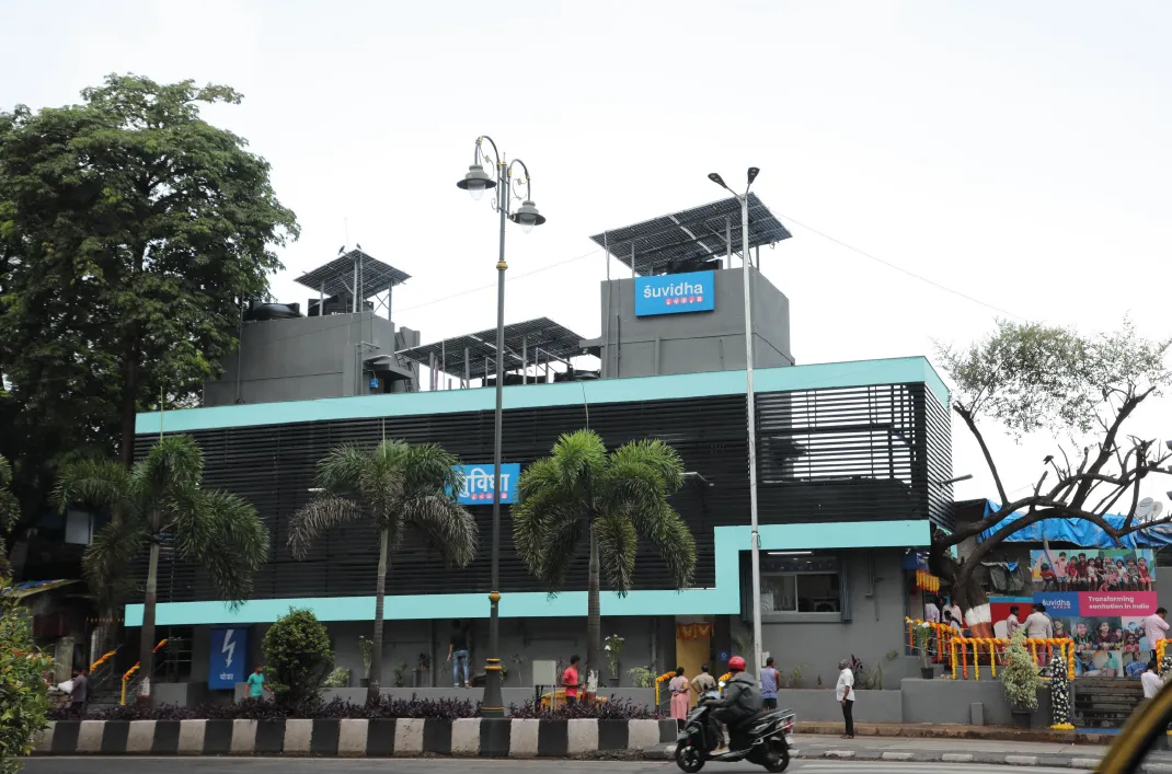 A bright, modern HUL Suvidha Center community hygiene hub in an informal settlement in Mumbai, showcasing a clean two-story building structure equipped to offer safe sanitation, purified drinking water, showers, and laundry facilities.